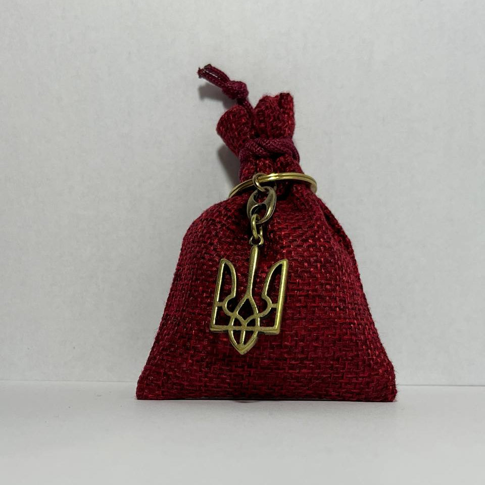Red drawstring bag with a gold trident pendant on a white background