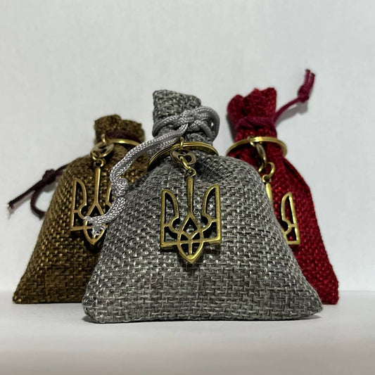Three drawstring bags with gold Ukrainian trident symbols on a white background